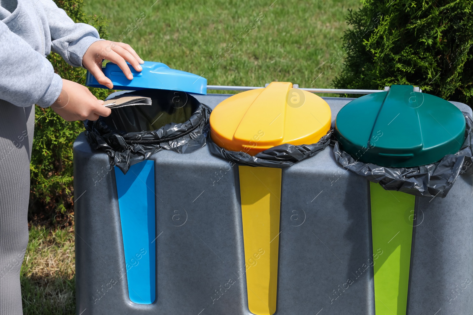 Photo of Woman throwing cardboard in bin outdoors, closeup. Recycling concept