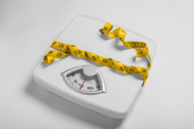 Photo of Weight loss concept. Scales and measuring tape on white background