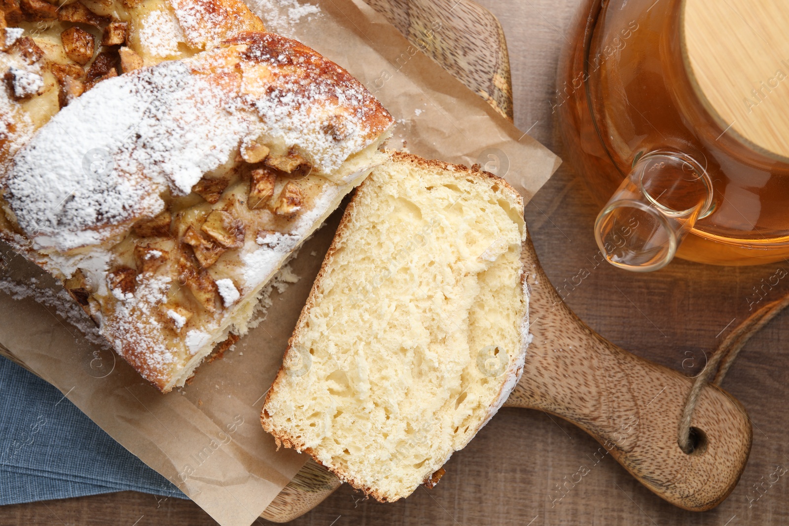 Photo of Delicious yeast dough cake and cup of tea on wooden table, flat lay