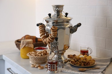 Photo of Traditional Russian samovar with treats on white table