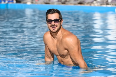 Photo of Handsome young man in swimming pool on sunny day