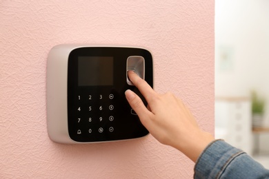 Woman scanning fingerprint on alarm system at home, closeup