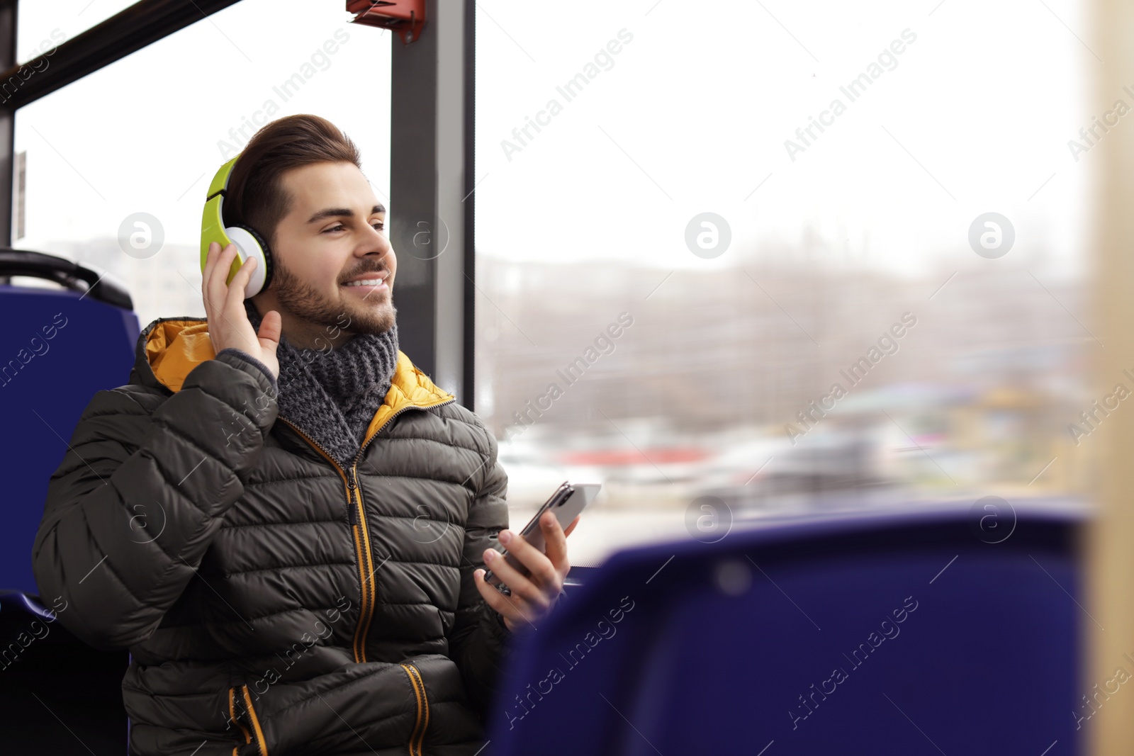 Photo of Young man listening to music with headphones in public transport