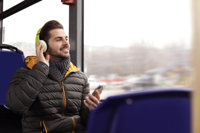 Young man listening to music with headphones in public transport