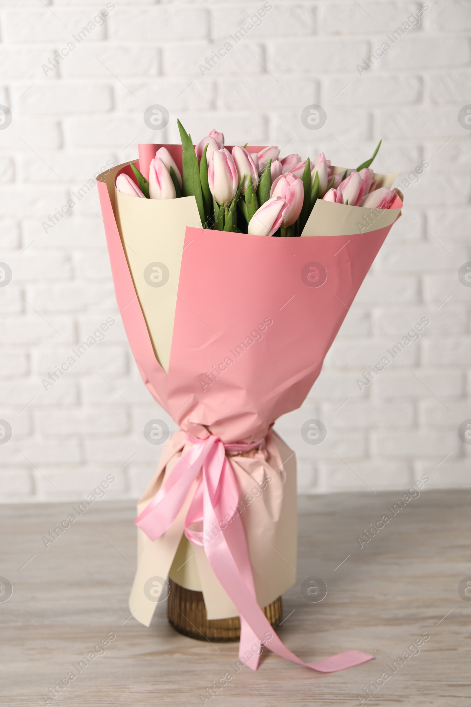 Photo of Beautiful bouquet of fresh pink tulips on light wooden table