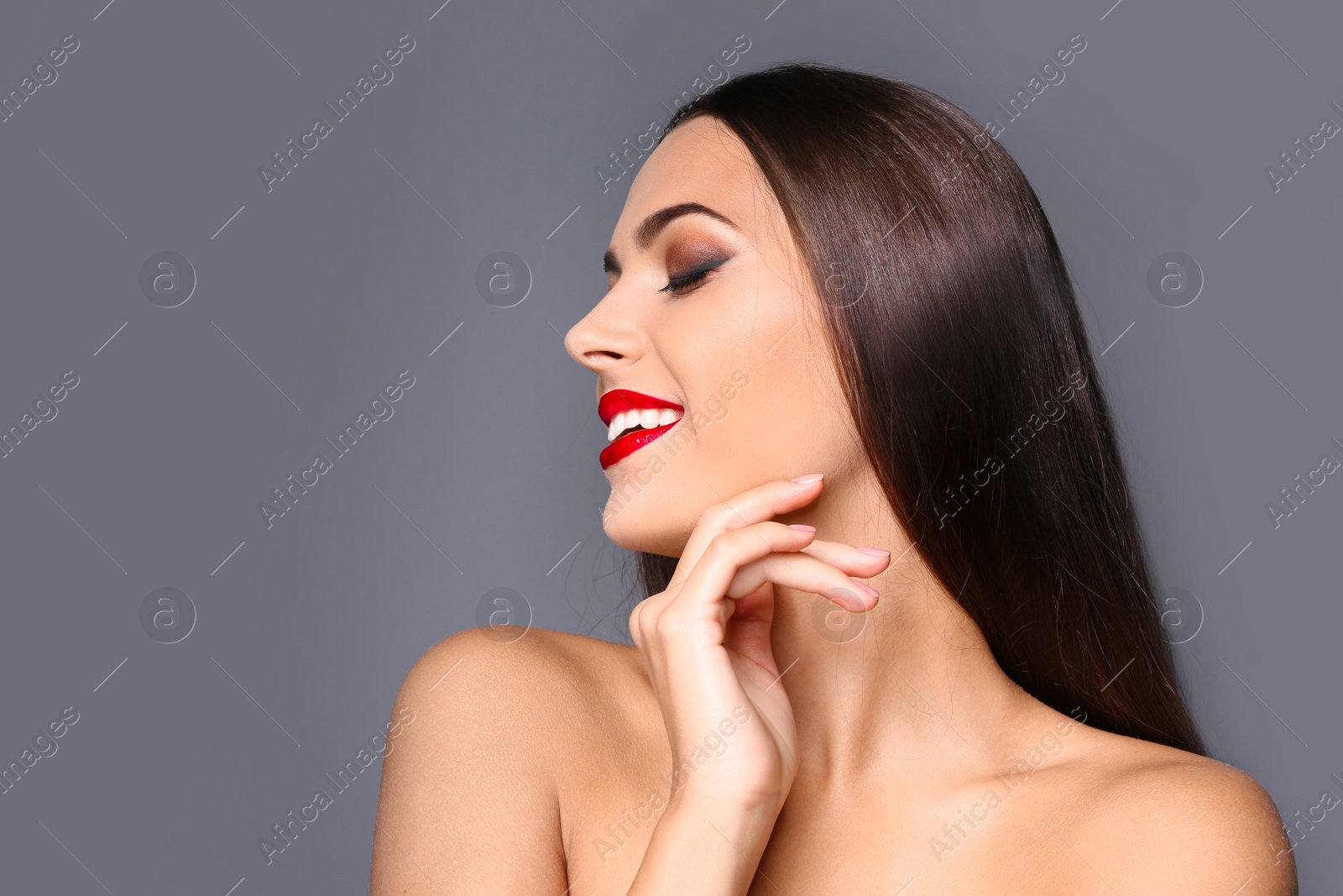 Photo of Portrait of beautiful young woman with red glossy lips on gray background