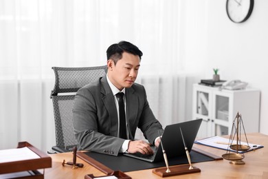 Notary working with laptop at wooden table in office