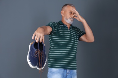 Man feeling bad smell from shoes on color background. Air freshener