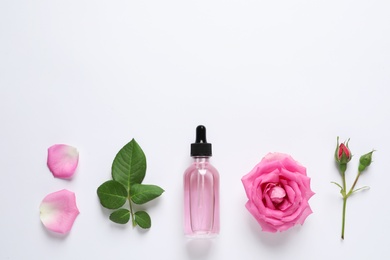Photo of Composition with rose essential oil and flowers on white background, top view