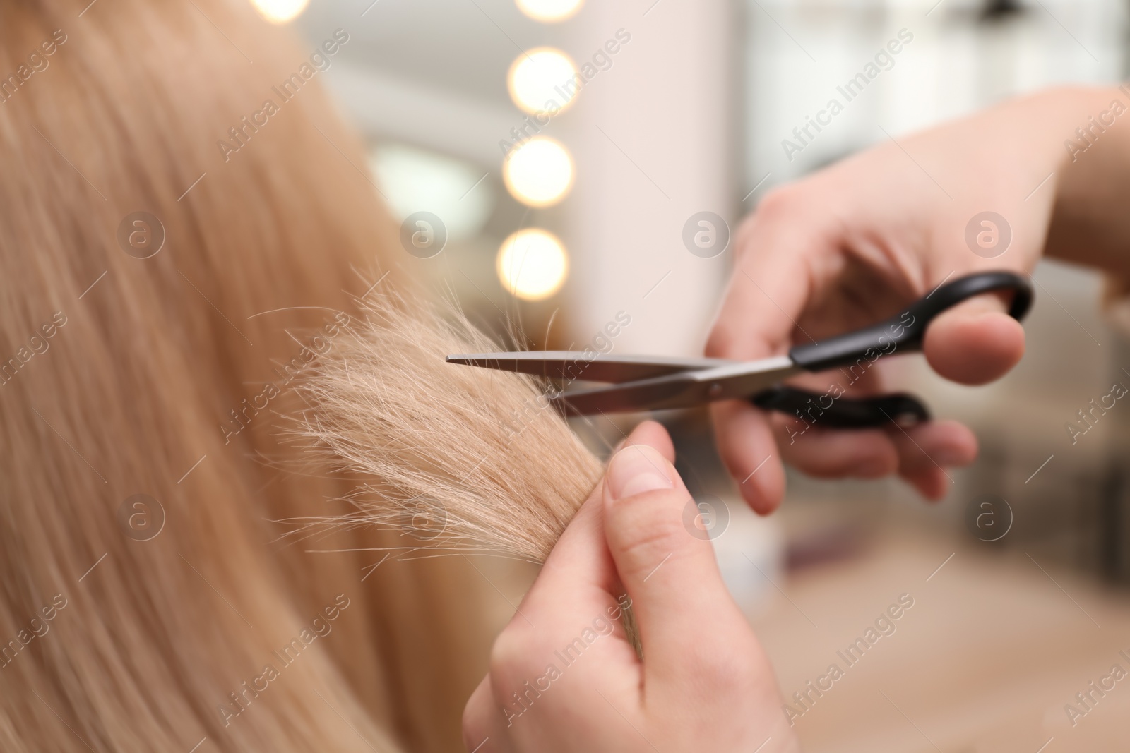 Photo of Stylist cutting hair of client in professional salon, closeup