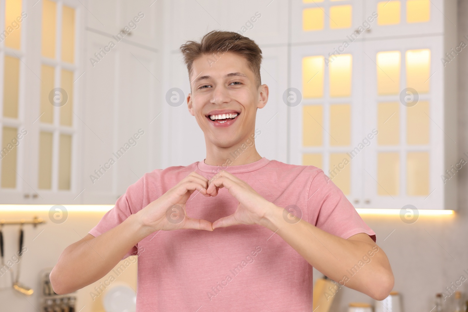Photo of Happy man showing heart gesture with hands at home
