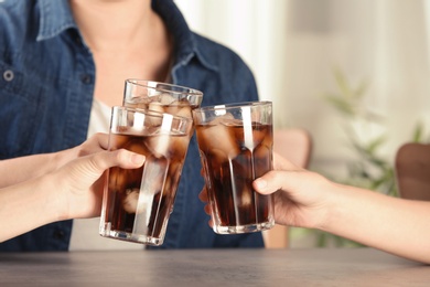 Photo of Friends with glasses of tasty refreshing cola at table, closeup view