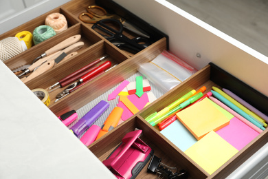 Photo of Stationery and sewing accessories in open desk drawer indoors, closeup