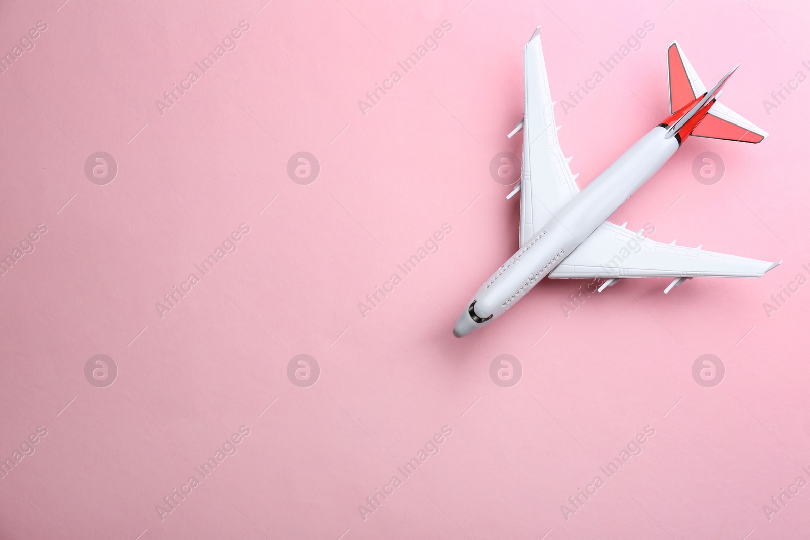 Photo of Toy airplane on pink background, top view. Space for text