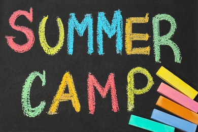 Photo of Blackboard with inscription SUMMER CAMP chalked in different colors, closeup