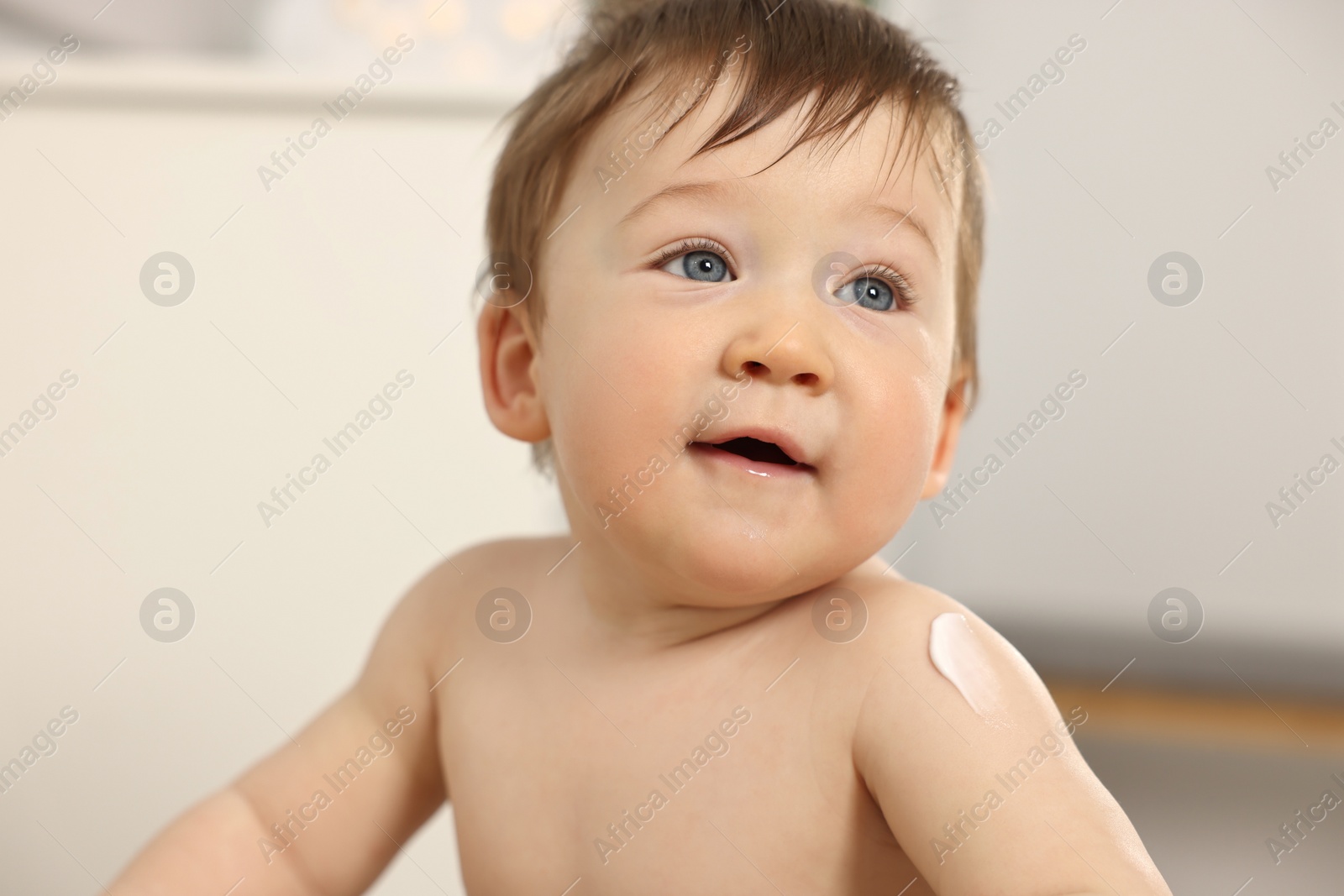 Photo of Cute little baby with moisturizing cream on body indoors