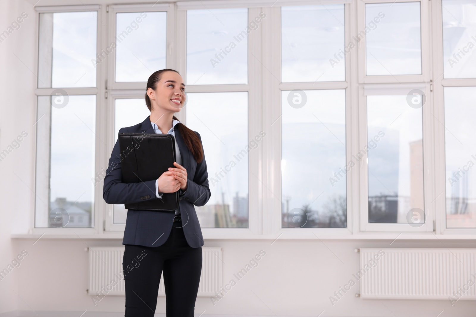 Photo of Happy real estate agent with leather portfolio in new apartment