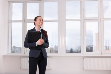 Happy real estate agent with leather portfolio in new apartment