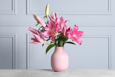 Beautiful pink lily flowers in vase on light grey table indoors