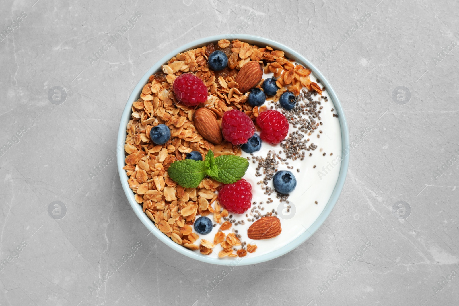 Photo of Tasty homemade granola with yogurt and berries on light grey table, top view. Healthy breakfast