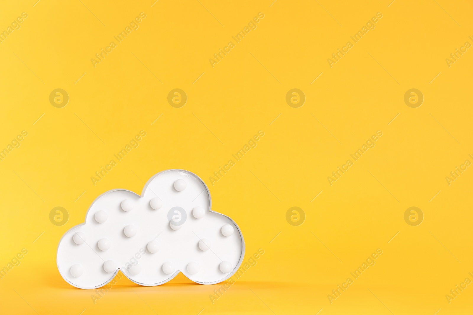 Photo of Stylish cloud shaped night lamp on yellow background. Space for text