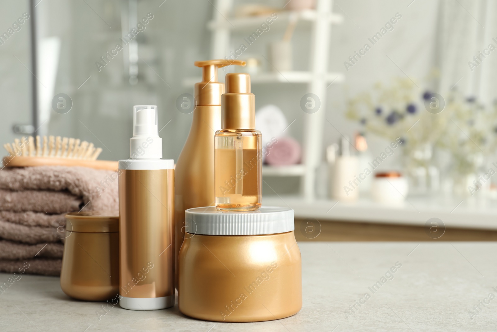 Photo of Set of hair care cosmetic products on light grey stone table in bathroom. Space for text