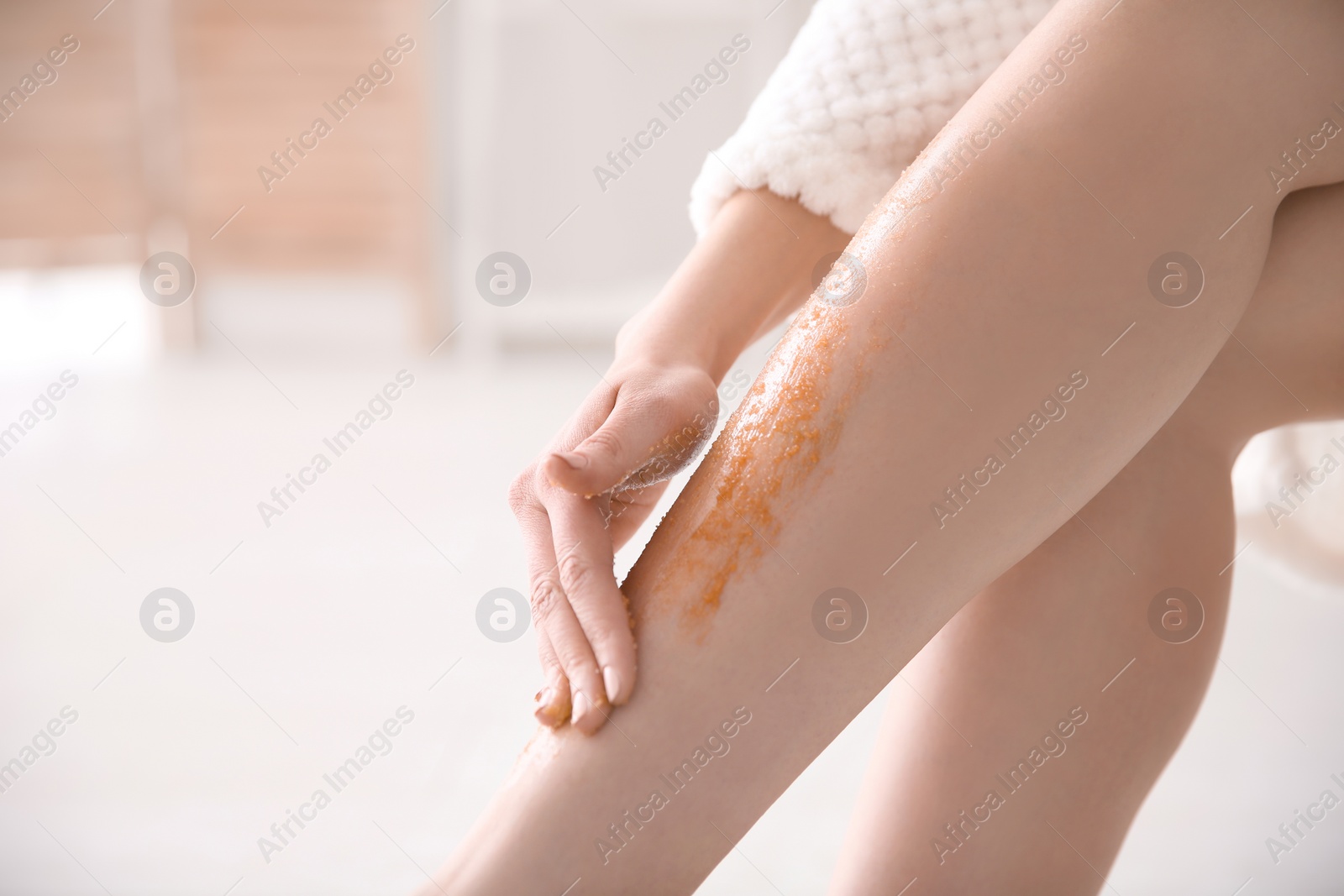 Photo of Woman applying body scrub on legs, closeup