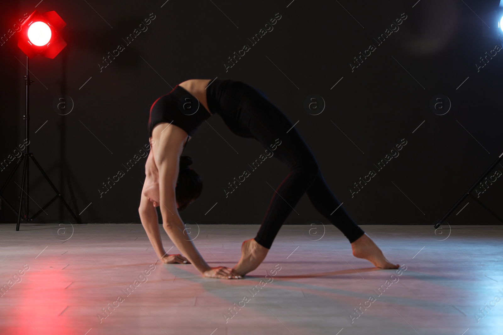 Photo of Young professional acrobat exercising in dark studio