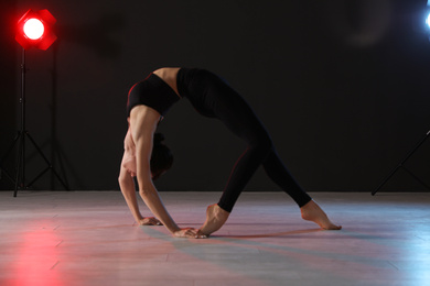 Young professional acrobat exercising in dark studio