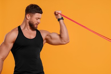 Young man exercising with elastic resistance band on orange background