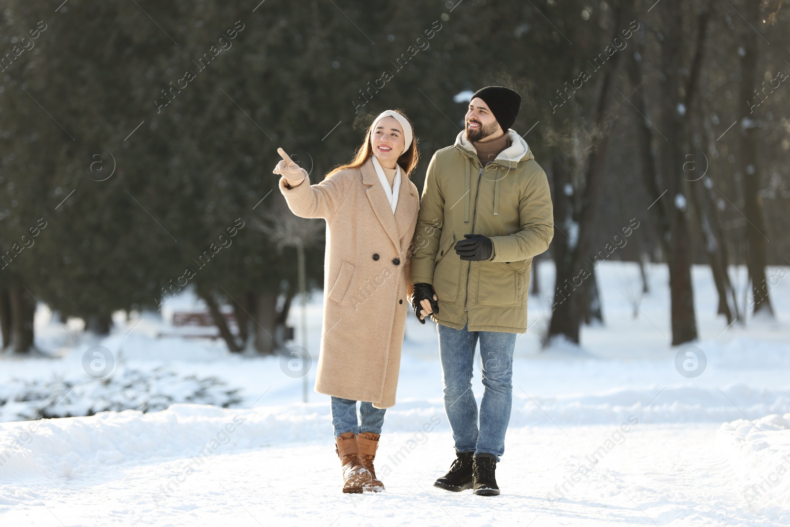 Photo of Happy young couple walking in snowy park on winter day