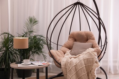 Photo of Comfortable place for rest with hanging chair near window in room