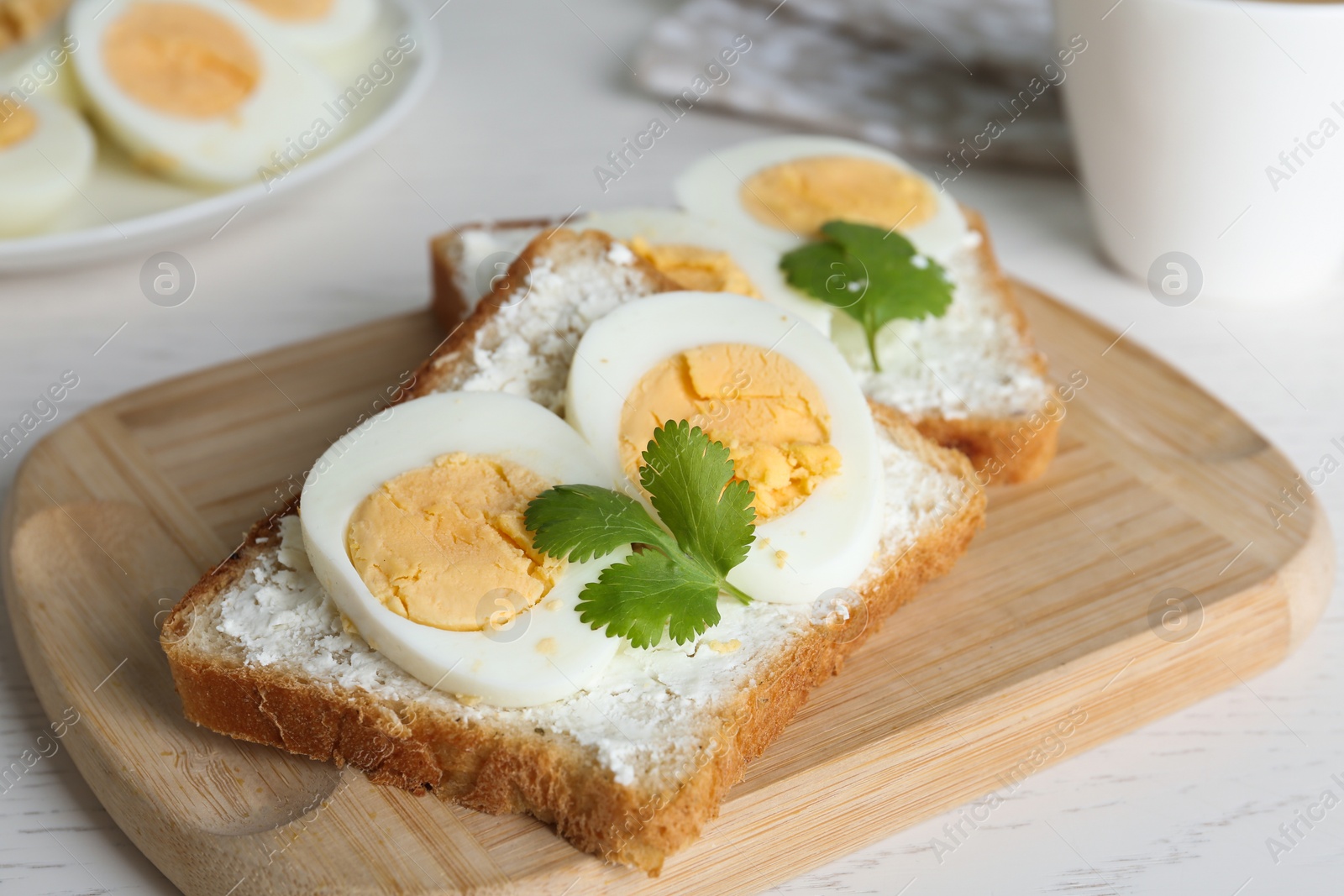 Photo of Tasty sandwiches with boiled eggs on wooden board, closeup