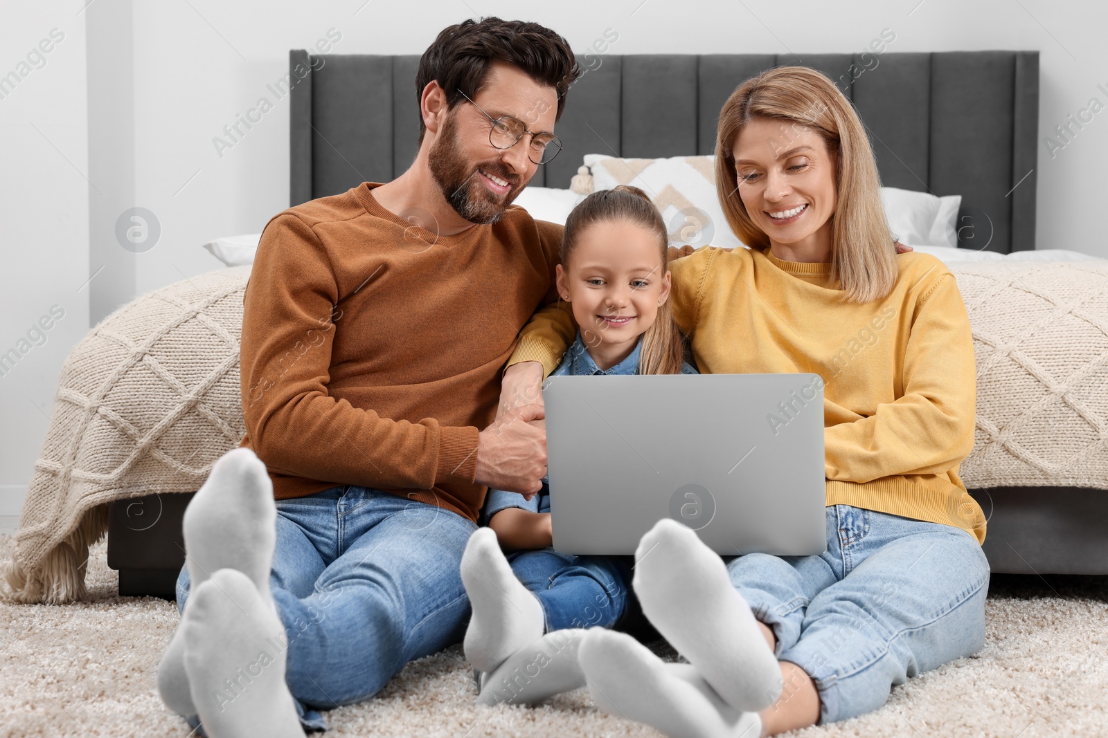 Photo of Happy family with laptop on floor at home