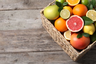 Photo of Different cut and whole citrus fruits on wooden table, above view. Space for text