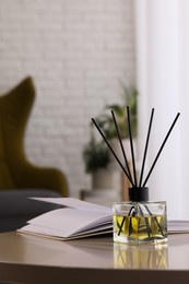 Photo of Reed diffuser on white table indoors. Cozy atmosphere
