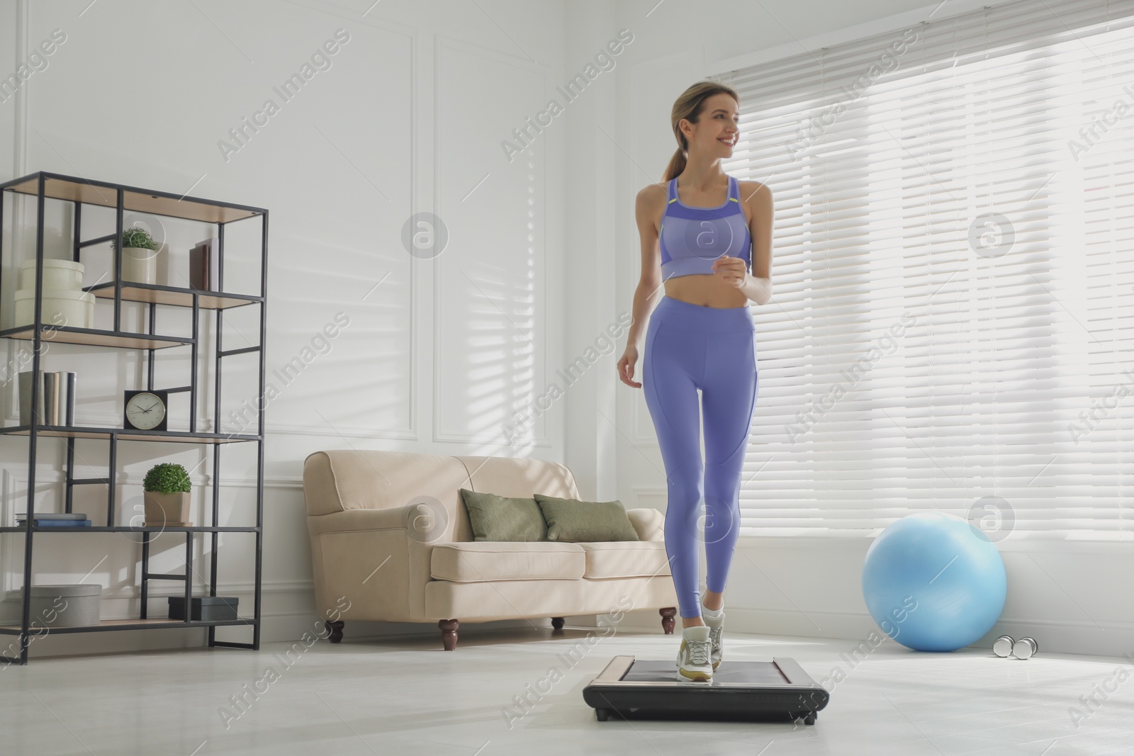 Photo of Sporty woman training on walking treadmill at home