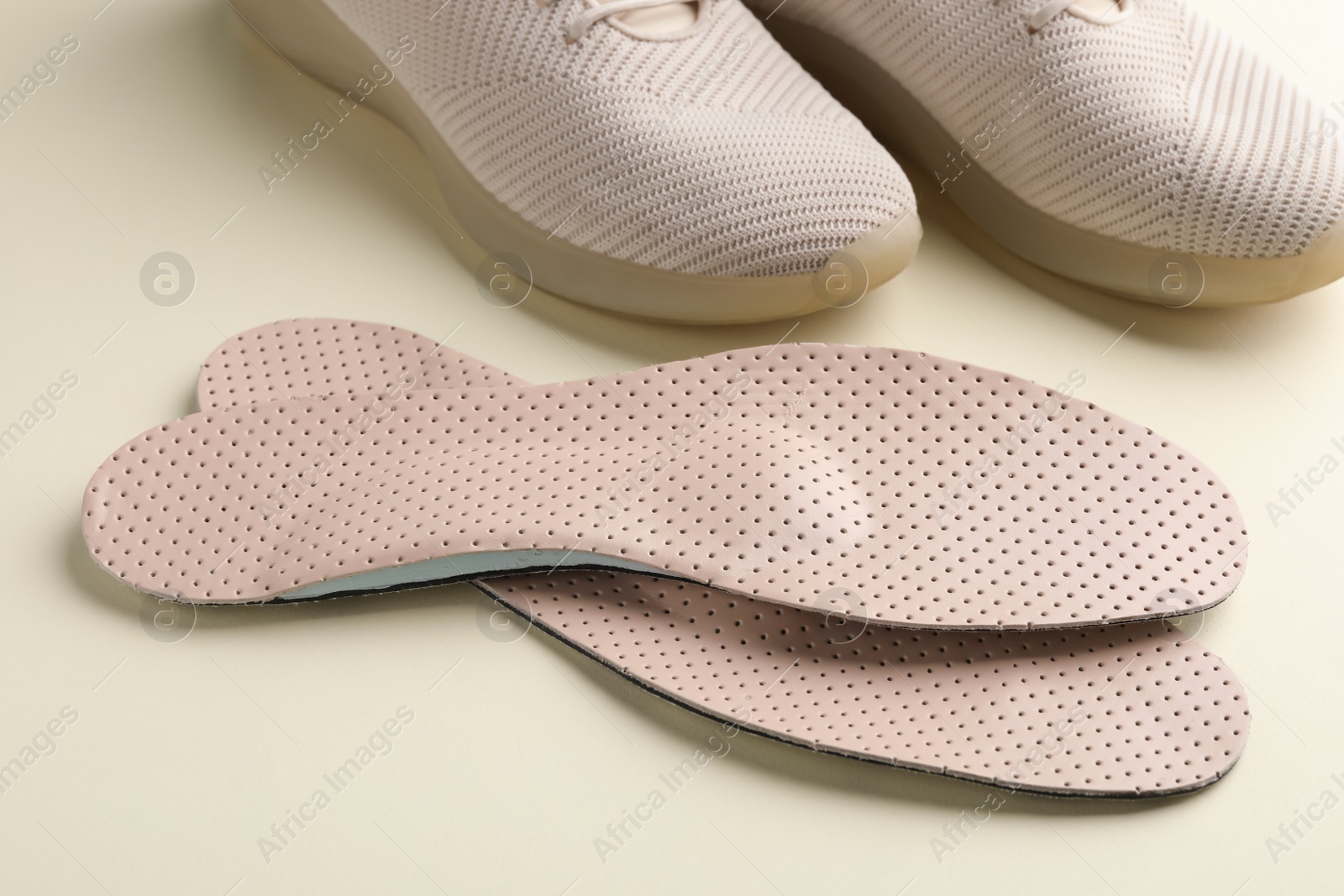 Photo of Beige orthopedic insoles and shoes on beige background