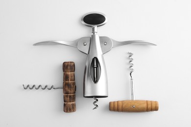 Different corkscrews on white background, flat lay