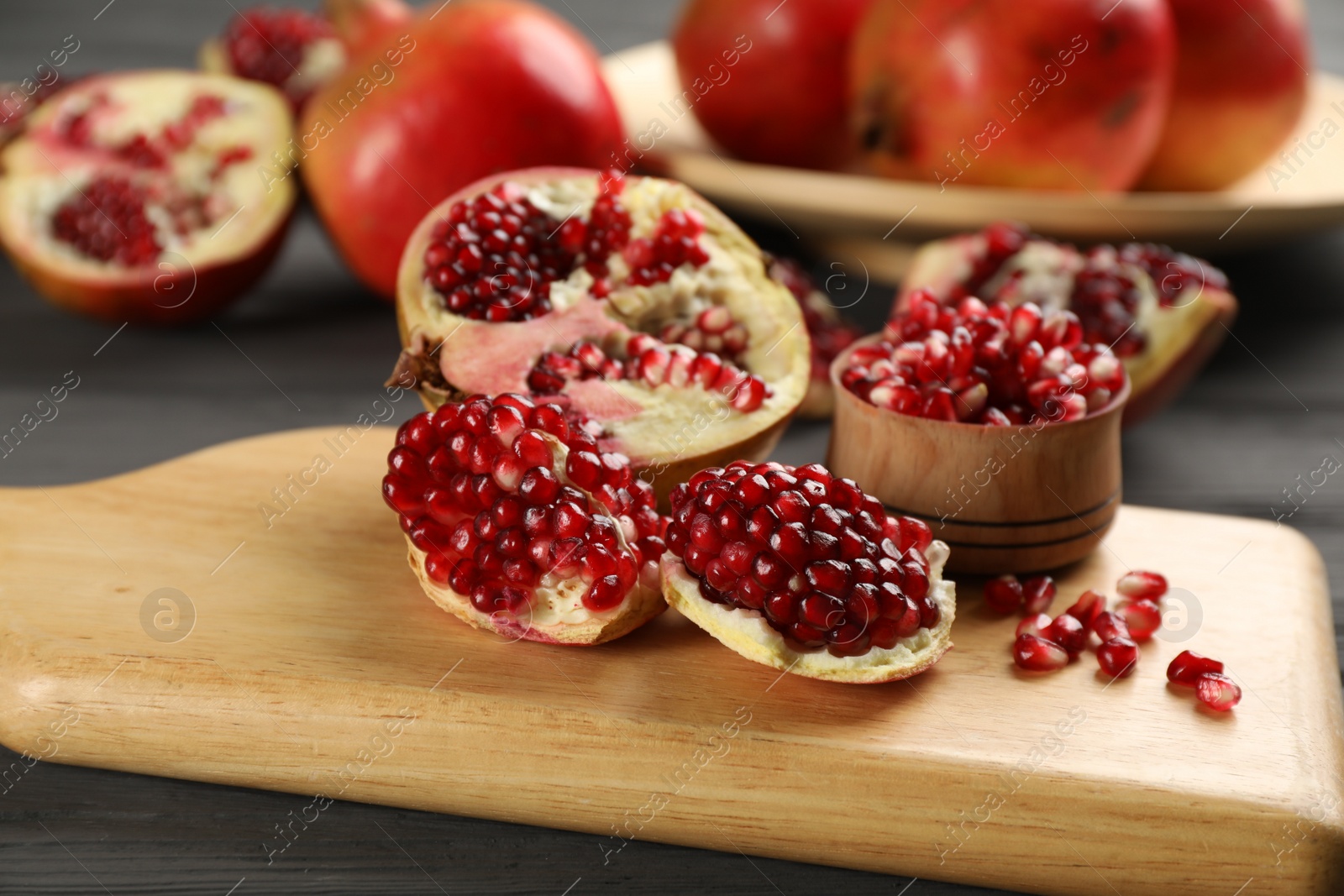 Photo of Delicious ripe pomegranates on grey wooden table