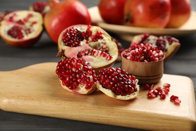 Photo of Delicious ripe pomegranates on grey wooden table