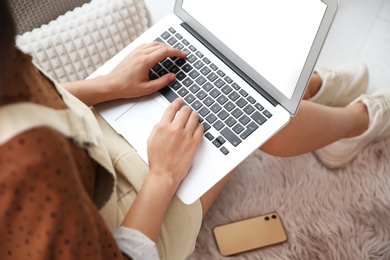 Young woman working with laptop at home office, closeup