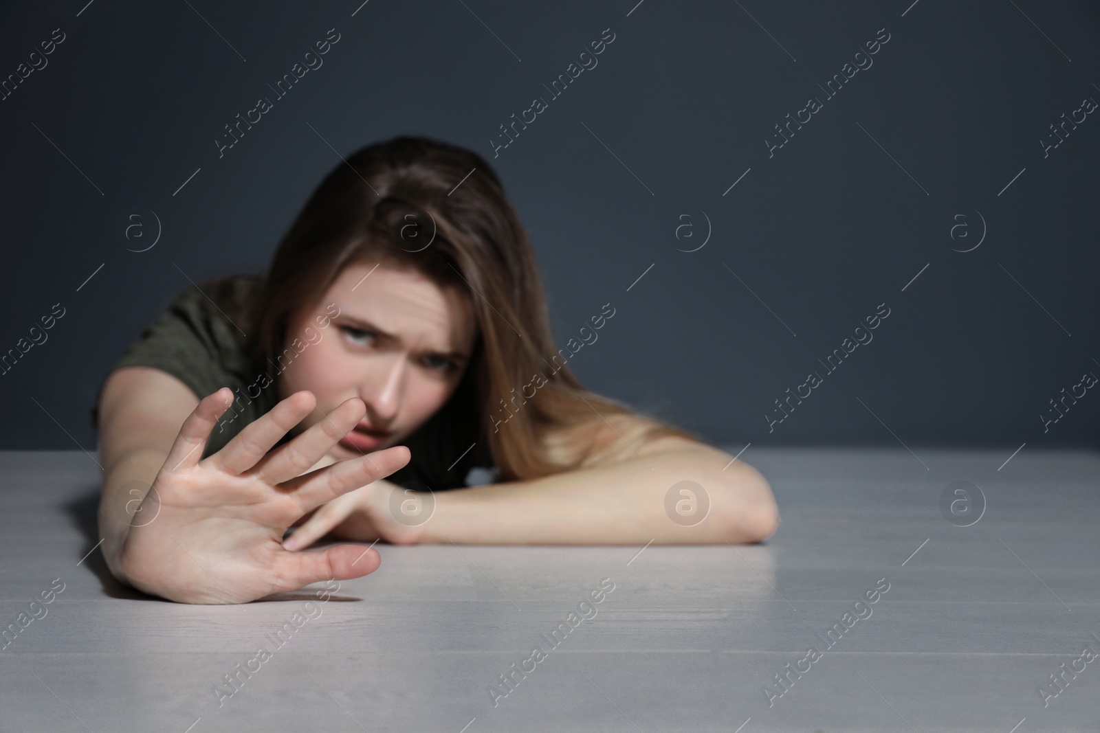 Photo of Young woman making stop gesture while lying on floor indoors. Space for text