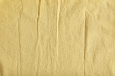 Crumpled pale yellow fabric as background, top view