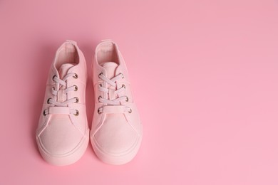 Photo of Pair of stylish canvas shoes on pink background. Space for text