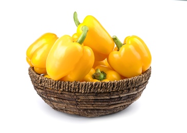 Wicker bowl of ripe yellow bell peppers isolated on white