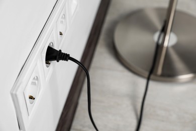 Floor lamp plugged into wall power socket indoors, closeup. Space for text
