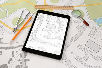 Photo of Office stationery and tablet on cadastral maps of territory with buildings