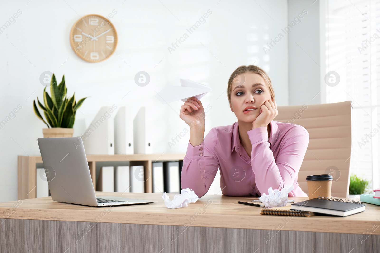 Photo of Lazy office worker playing with paper plane at desk indoors