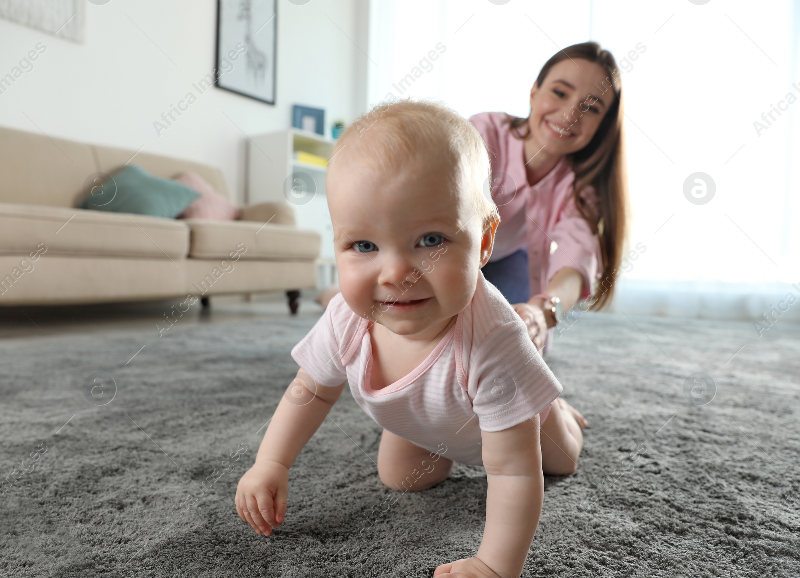 Photo of Adorable little baby crawling near mother at home